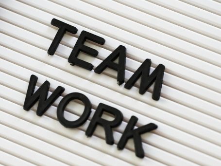 Schwarze Buchstaben bilden das Wort "TEAM WORK" auf einem hellen Hintergrund.