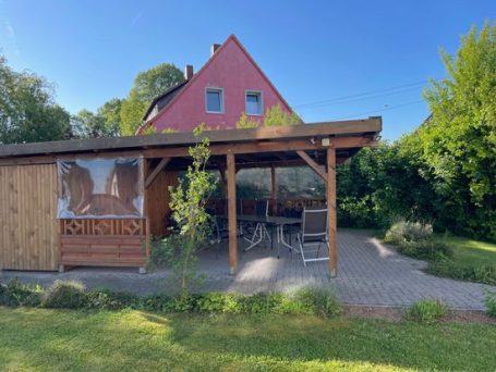 Außenbereich Außenansicht eines Hauses mit Terrasse und Garten, umgeben von Bäumen und Sträuchern.