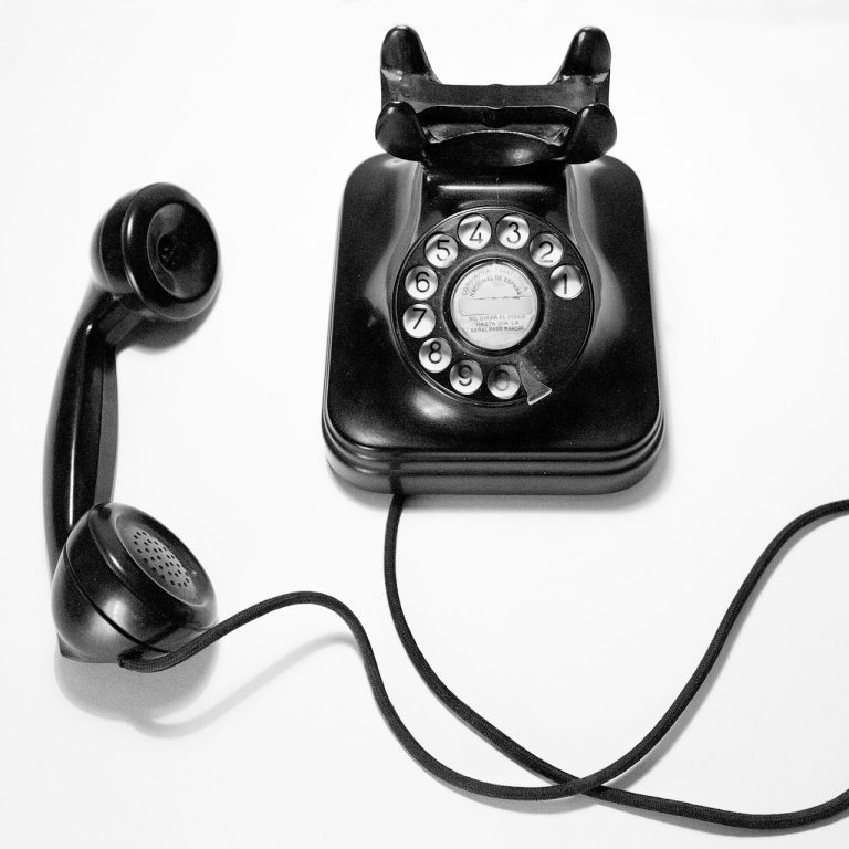 Schwarz-weißes Wählscheibentelefon mit abgezogenem Hörer.