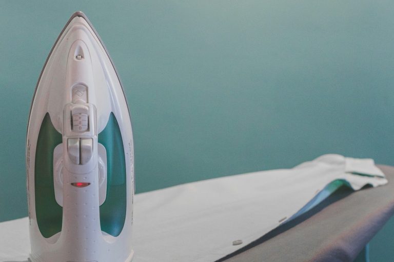 Hauswirtschaftliche Leistungen Dampfstation und glattes, gebügeltes Hemd auf einem Bügelbrett.