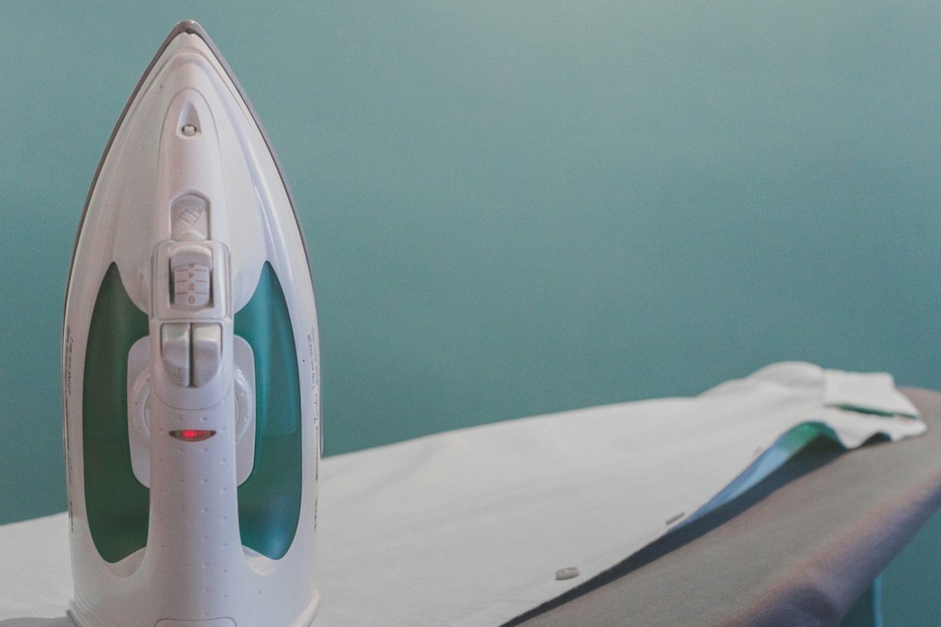 Dampfstation und glattes, gebügeltes Hemd auf einem Bügelbrett.