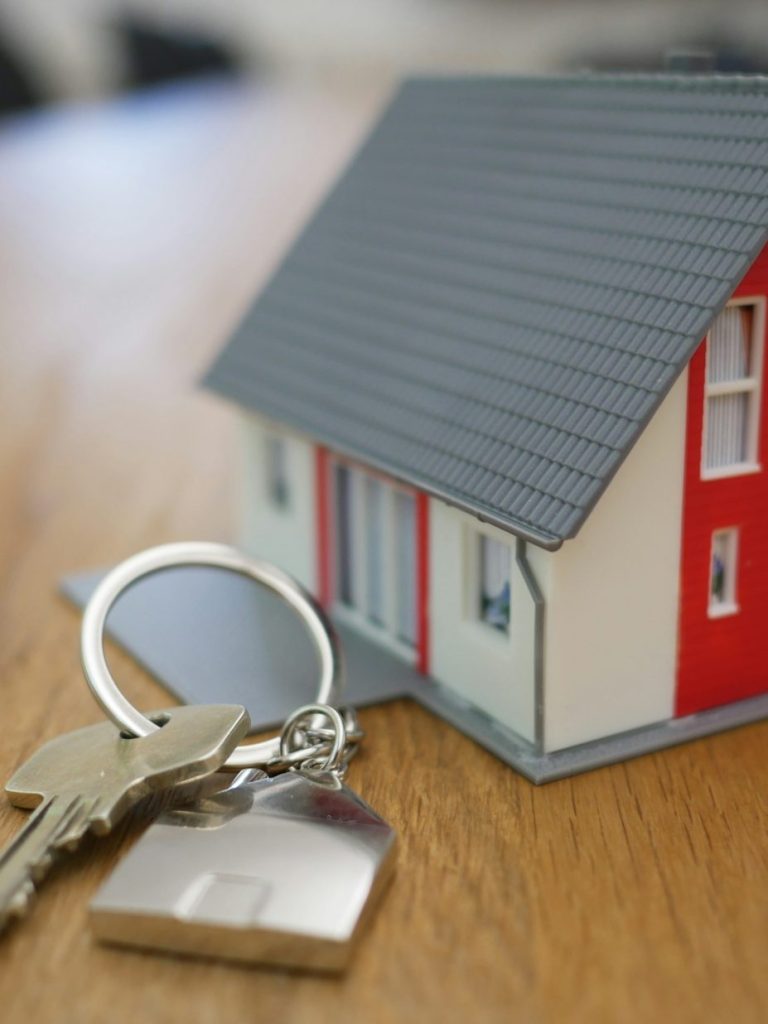 Ambulant betreute WGs Hausmodell mit Schlüsselbund auf einem Holztisch.